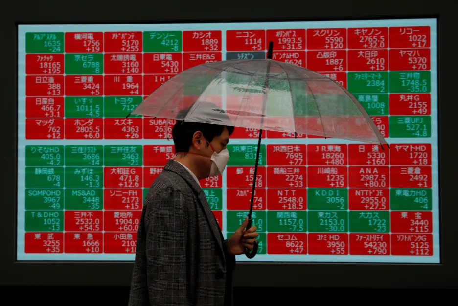 Muž v Tokiu míjí tabuli ukazující pohyby akcií na burzách