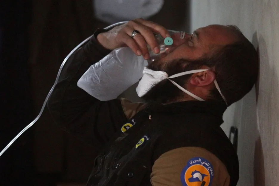 Příslušník civilní obrany používá po útoku armády v Chán Šajchún kyslíkovou masku
