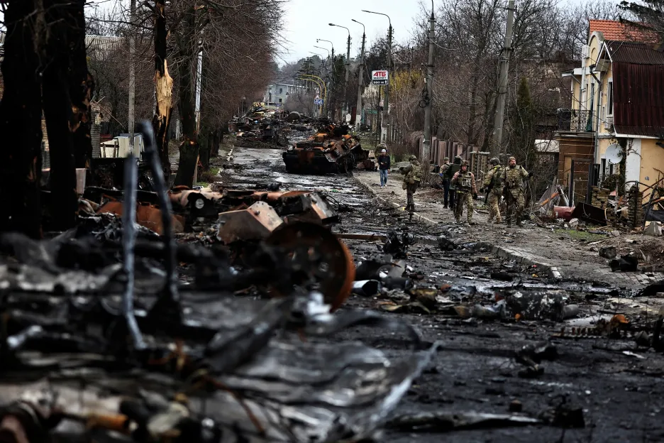 Ukrajinští vojáci procházejí kolem zničených ruských tanků ve městě Buča