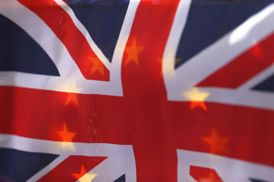 Vlajka Velké Británie a v pozadí prosvítající vlajka EU