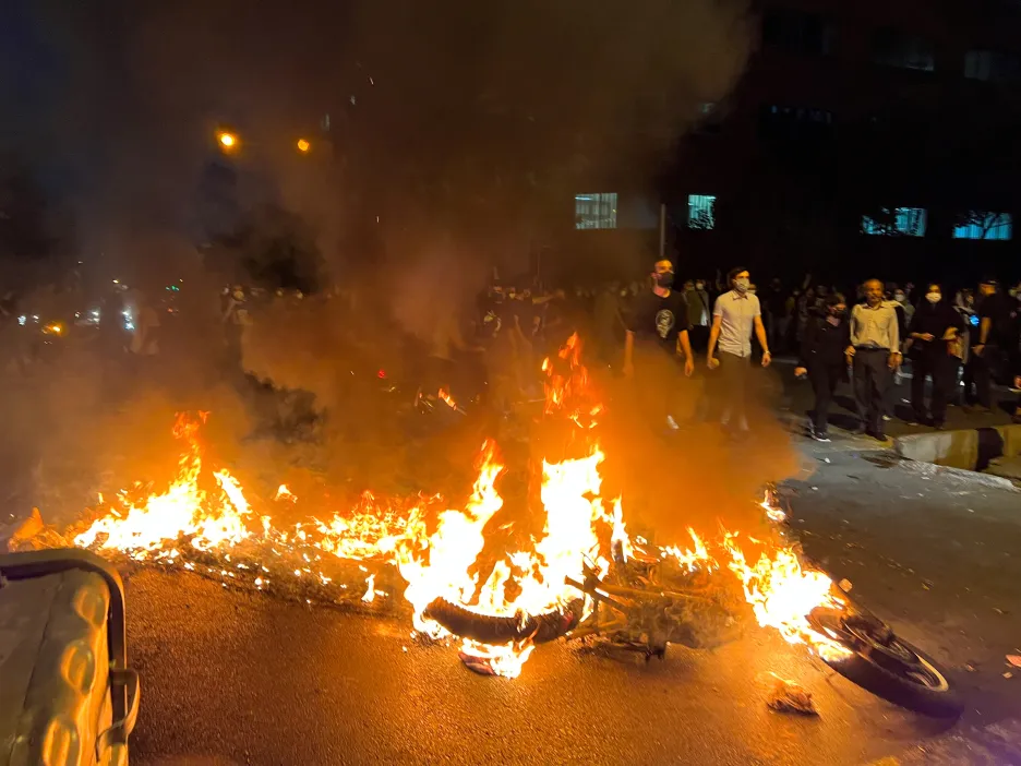 Hořící policejní motocykl při protestech v Teheránu
