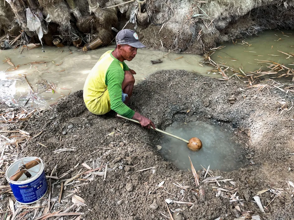 Indonéský farmář nabírá vodu z ručně vyhloubeného koryta