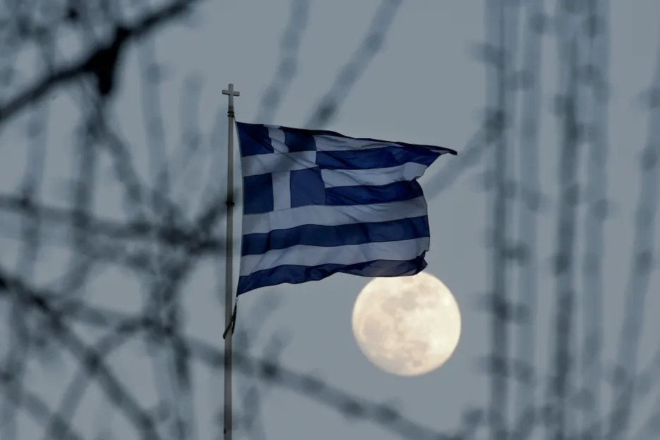 Řecká vlajka vlaje za svitu měsíce v Aténách