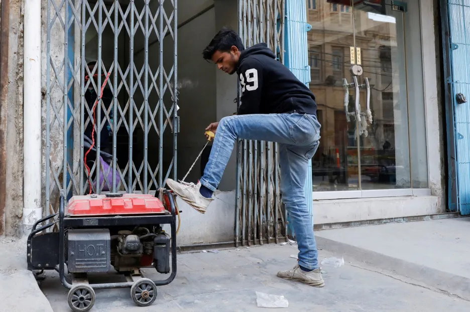 Obchodník spouští generátor před svou prodejnou v Karáčí