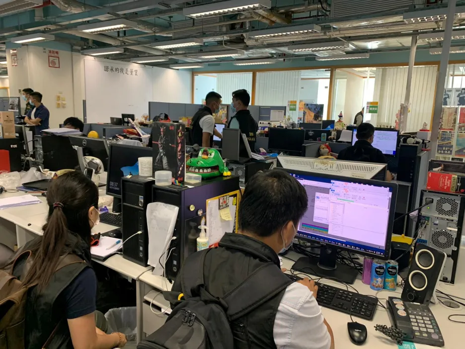 Policisté prohlížejí počítače v redakci deníku Apple Daily
