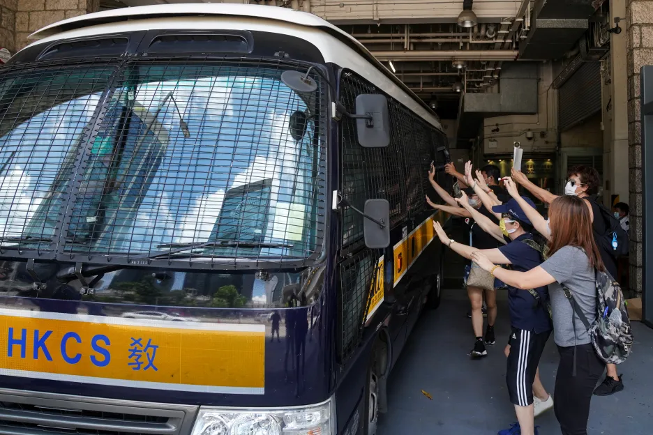 Podporovatelé Tong Ying Kita mávají na vůz, který ho transportuje do vězení