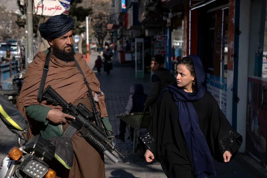 Afghánka prochází kolem hlídkujícího Taliba