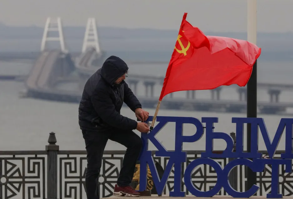 Muž věší sovětskou vlajku na vyhlídce na Krymský most