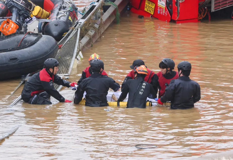 Záchranáři přenáší tělo oběti nalezené v tunelu poblíž Čchongdžu