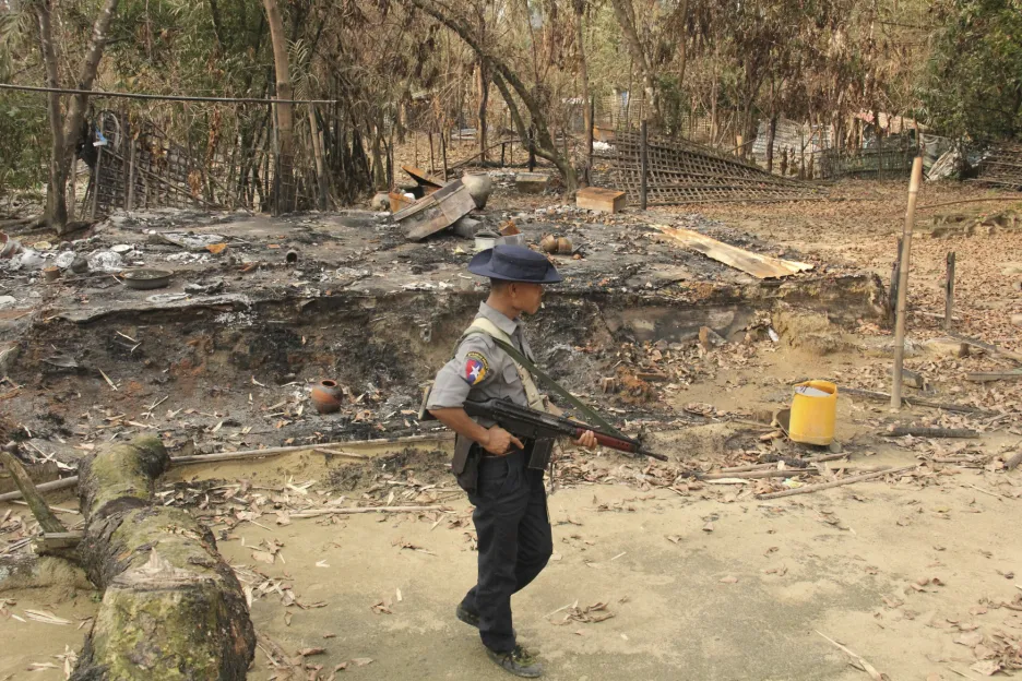 Voják v Myanmaru prochází kolem spáleného domu Rohingů