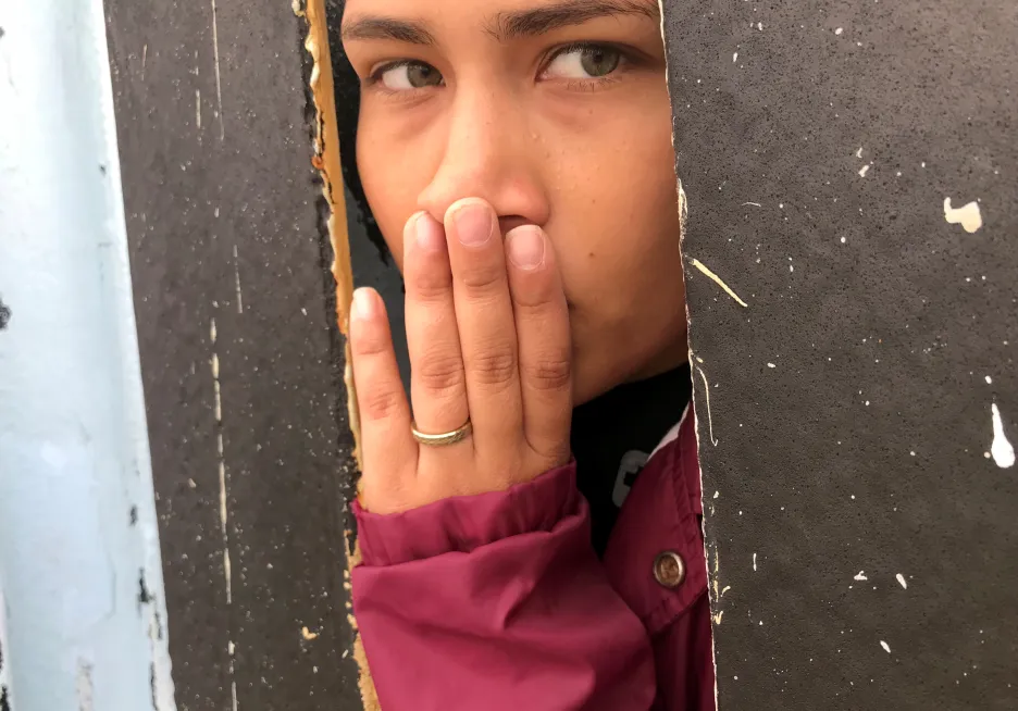Žena u zdi mezi Mexikem a USA dívající se z Tijuany na druhou stranu hranice
