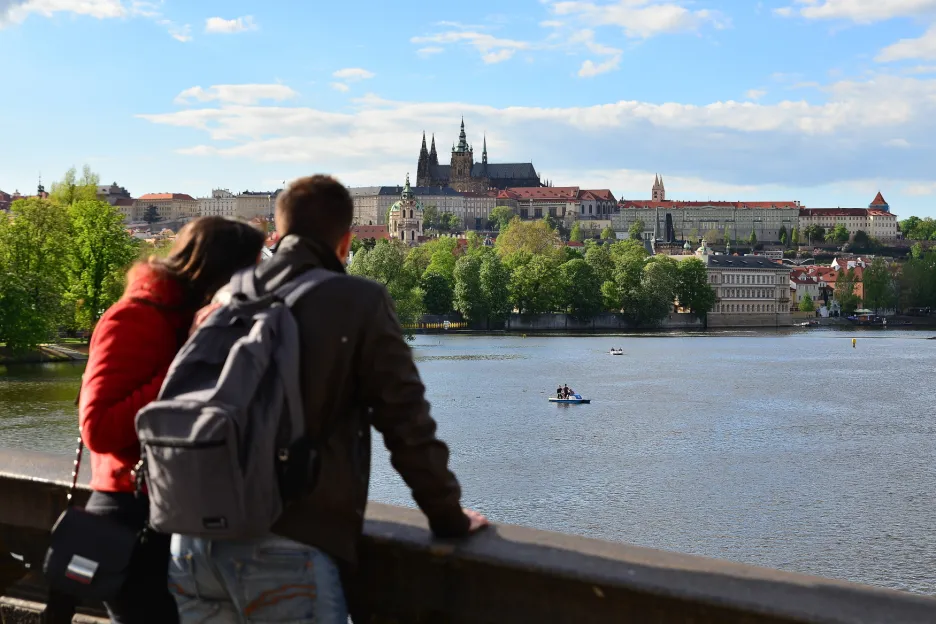 Turisté hledící na panorama s Pražským hradem a řekou Vltavou. 