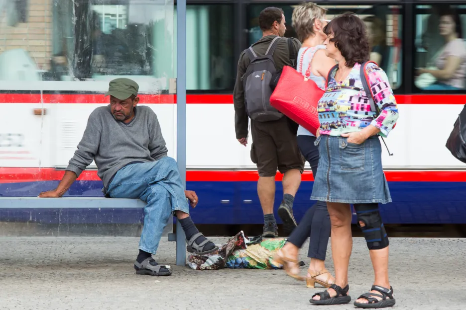 Bezdomovec na tramvajové zastávce v Olomouci