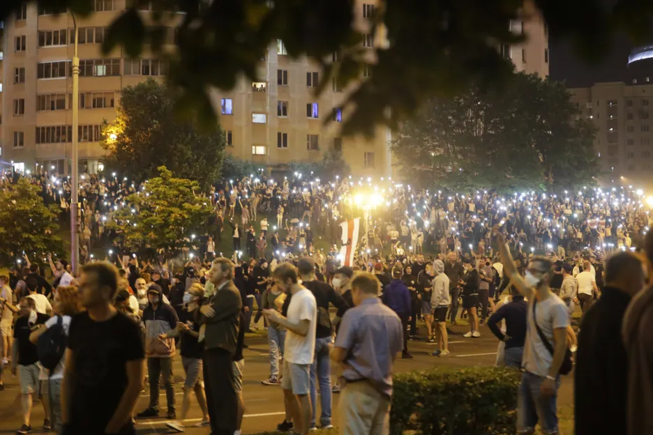 Lidé, demonstrující v centru Minsku, drží nad hlavami svítící displeje svých telefonů