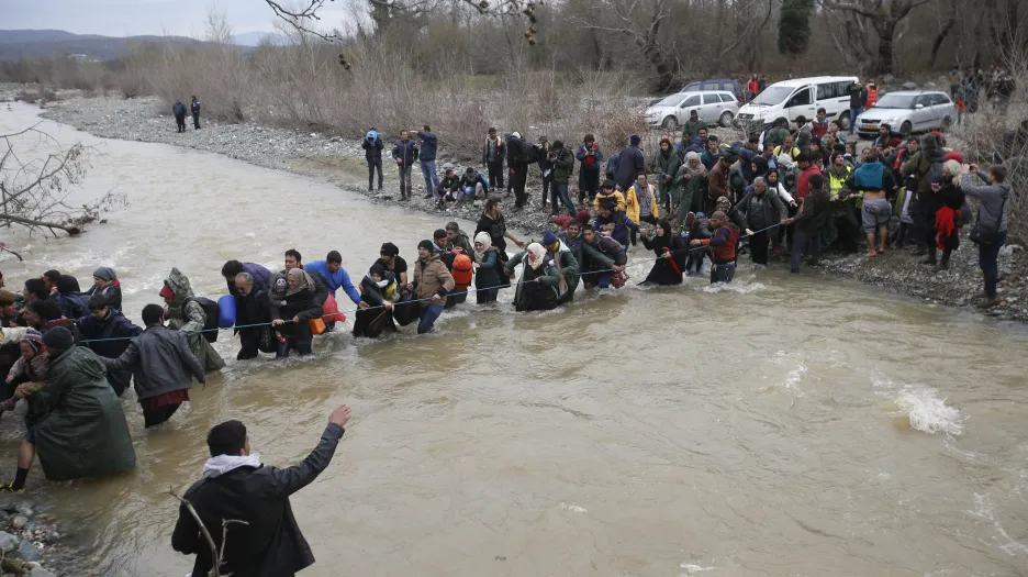 Uprchlíci a dobrovolníci vytvořili živý řetěz přes řeku u hranice Řecka a Makedonie