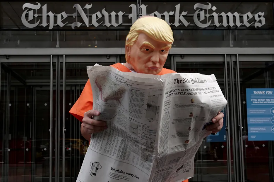 Aktivista Mike Hisey čte v masce Donalda Trumpa New York Times